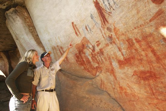 Guide zeigt Frau archäologische Schätze in Südafrika: Beeindruckende Felsmalereien von Menschen und Tieren
