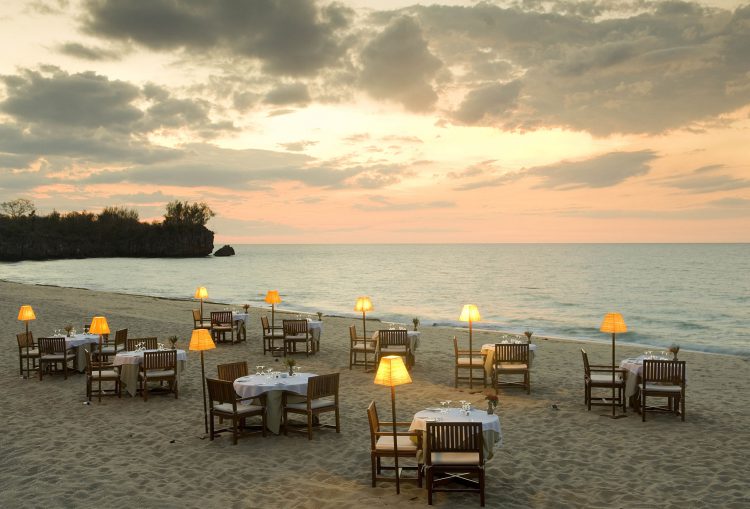 „digitale Detox“-madagascar-rhino-africa-travel-remote-places Auf einem Strand stehen viele Tische und Sesseln, daneben das Meer