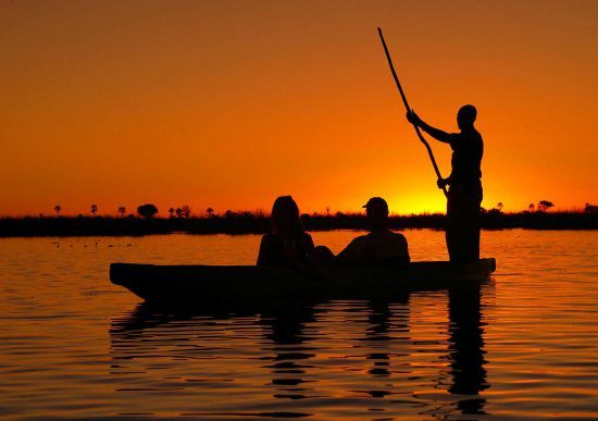 Silhueta de canoa ao pôr do sol no Delta do Okavango