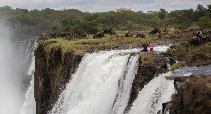 A man and woman swimming in the Devil's Pool in Zambia