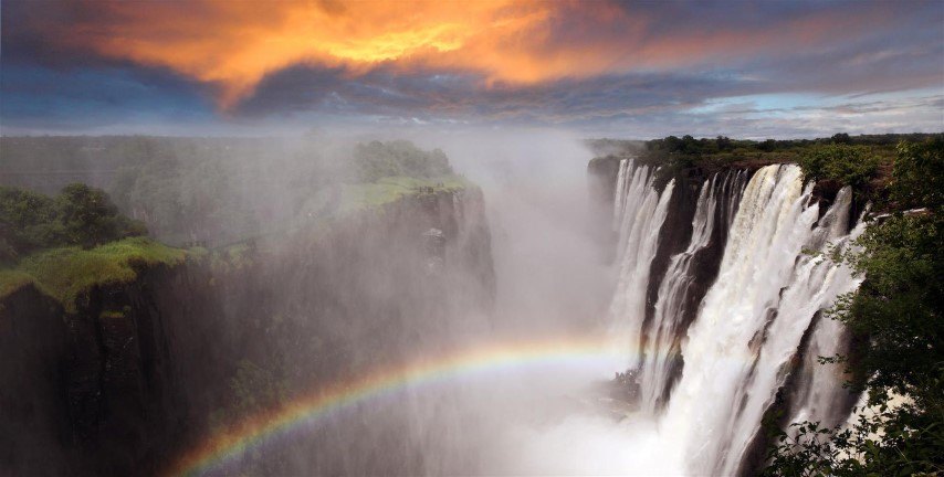 Ein Regenbogen bei Sonnenuntergang über den malerischen Victoria-Fällen in Sambia