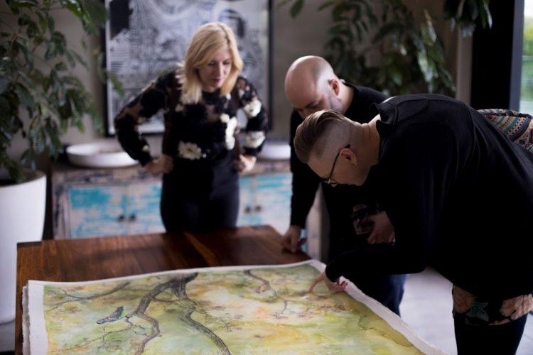 Les trois artistes impliqués dans la création des aquarelles signant leurs oeuvres.