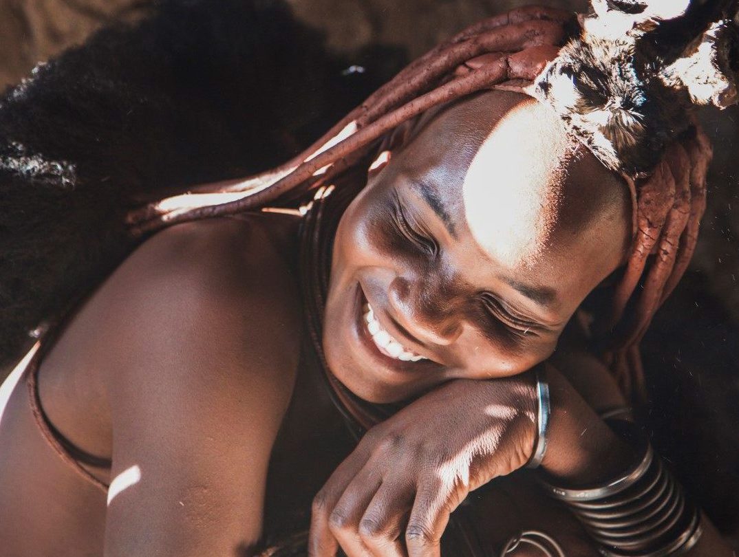 Uma mulher Himba sorri enquanto é iluminada pelo sol