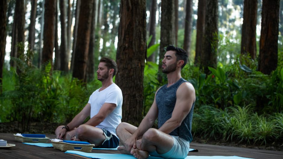 Wellness-Urlaub in Afrika: Zwei Männer meditieren im Regenwald von Ruanda