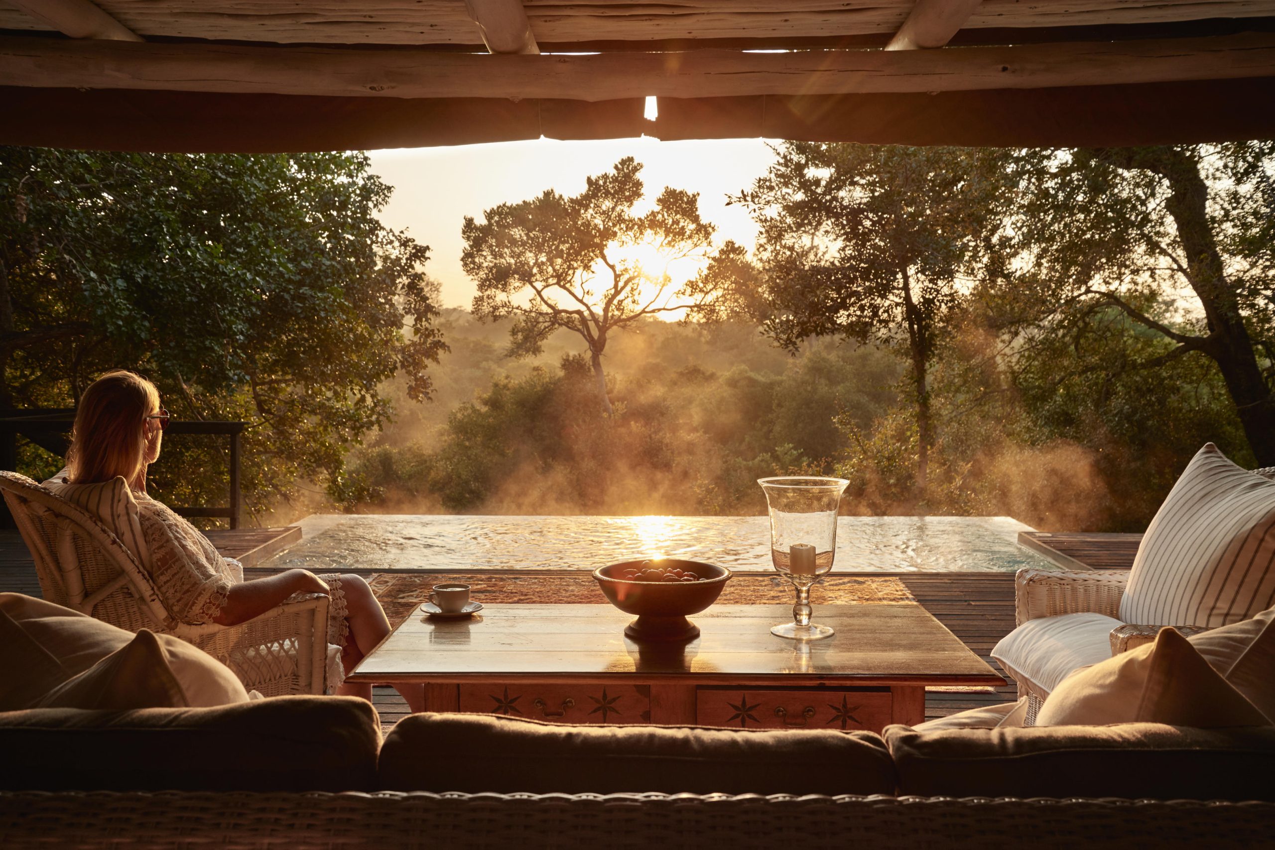 Woman sitting, looking out over the bush from a private deck
