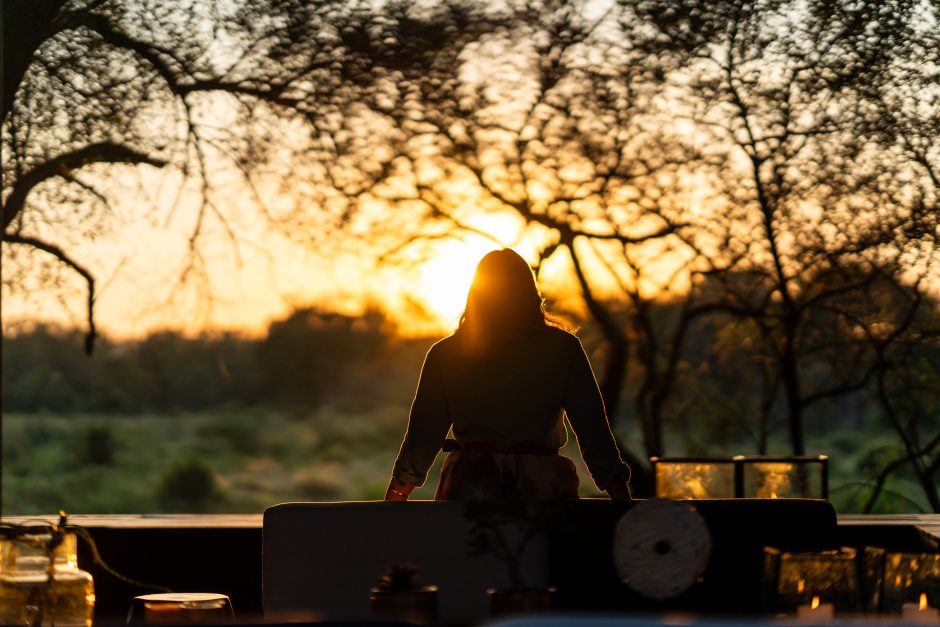 Woman leaning on the deck railing, watching the sunset