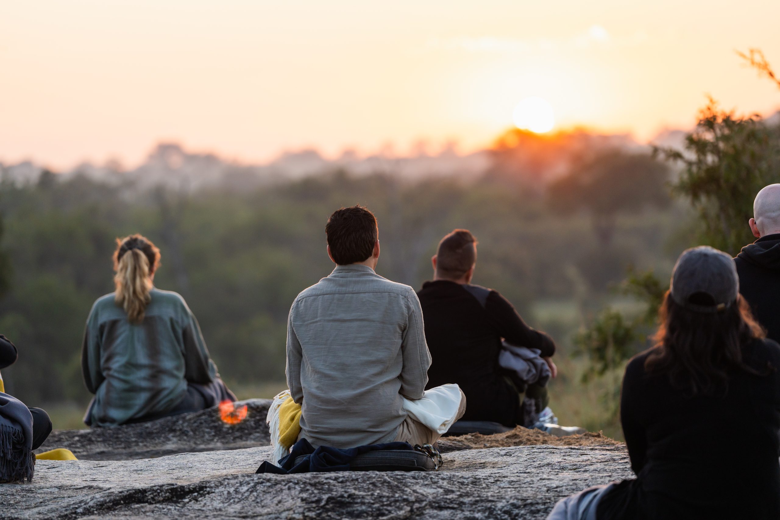 iglta-at-silvan-safari-copyrights-rhino-africa-063 A group of people doing a sunrise meditation from the top of a large rock in the Sabi Sand Game Reserve, looking out over the bush