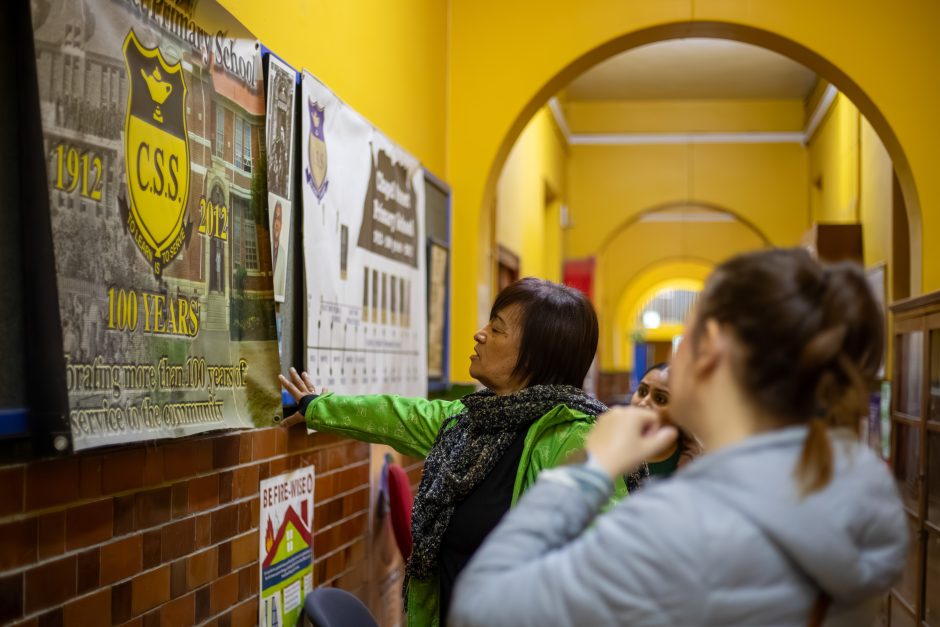 madiba-day-chapel-street-school-painting-2025-10 Rhino Africa volunteers review a historical school banner in a brightly colored hallway