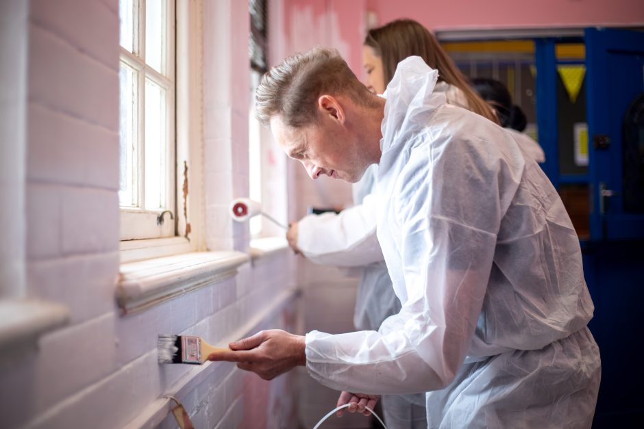 madiba-day-chapel-street-school-painting-2025-178 A Rhino Africa volunteer carefully paints a classroom wall near a window during a Mandela Day project