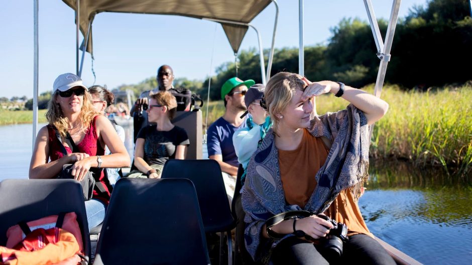 Travellers sit on a guided boat safari, showing how safe are safari tours when backed by expert planning and support.