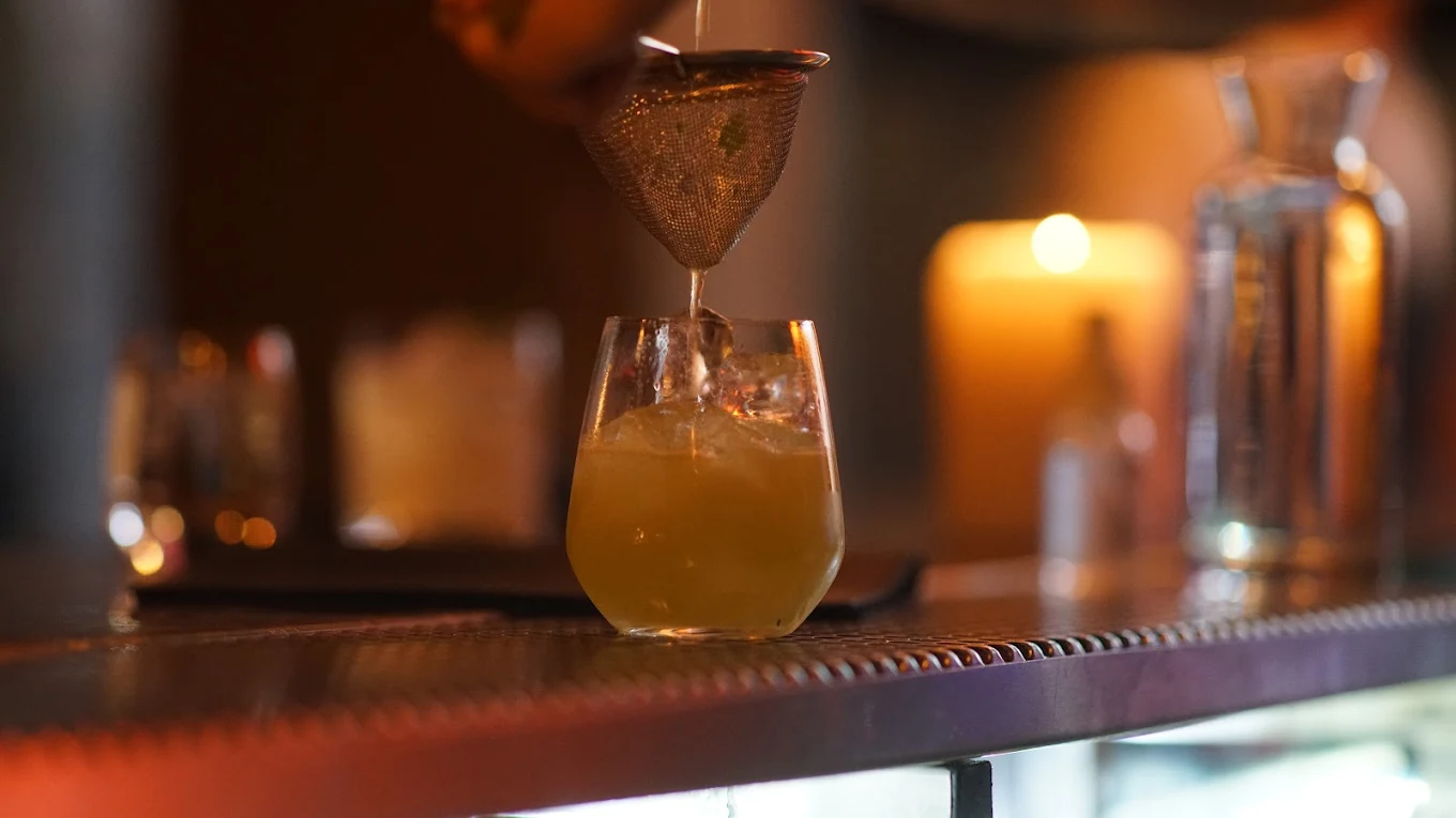 A cocktail being prepared in a candle-lit atmosphere