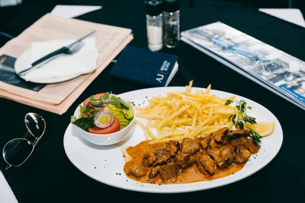 Espresso-Parkhurst A plate of meat, chips, and salad on a café table