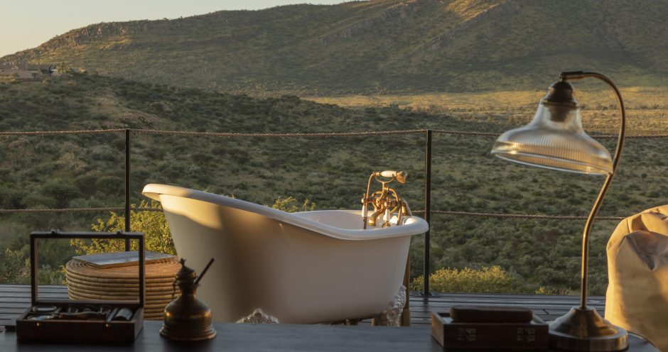 A slipper-style bath on a deck outdoors with a view of rolling green hills at Gmundner Lodge