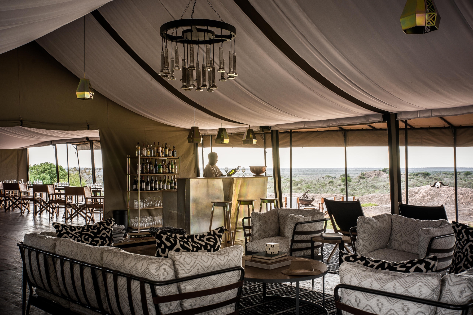 A&K-Sanctuary-Kichakani-Serengeti-Camp-bar A fully furnished lounge and bar setup inside one of Africa’s mobile tented camps, complete with chandeliers, drinks service, and panoramic views.