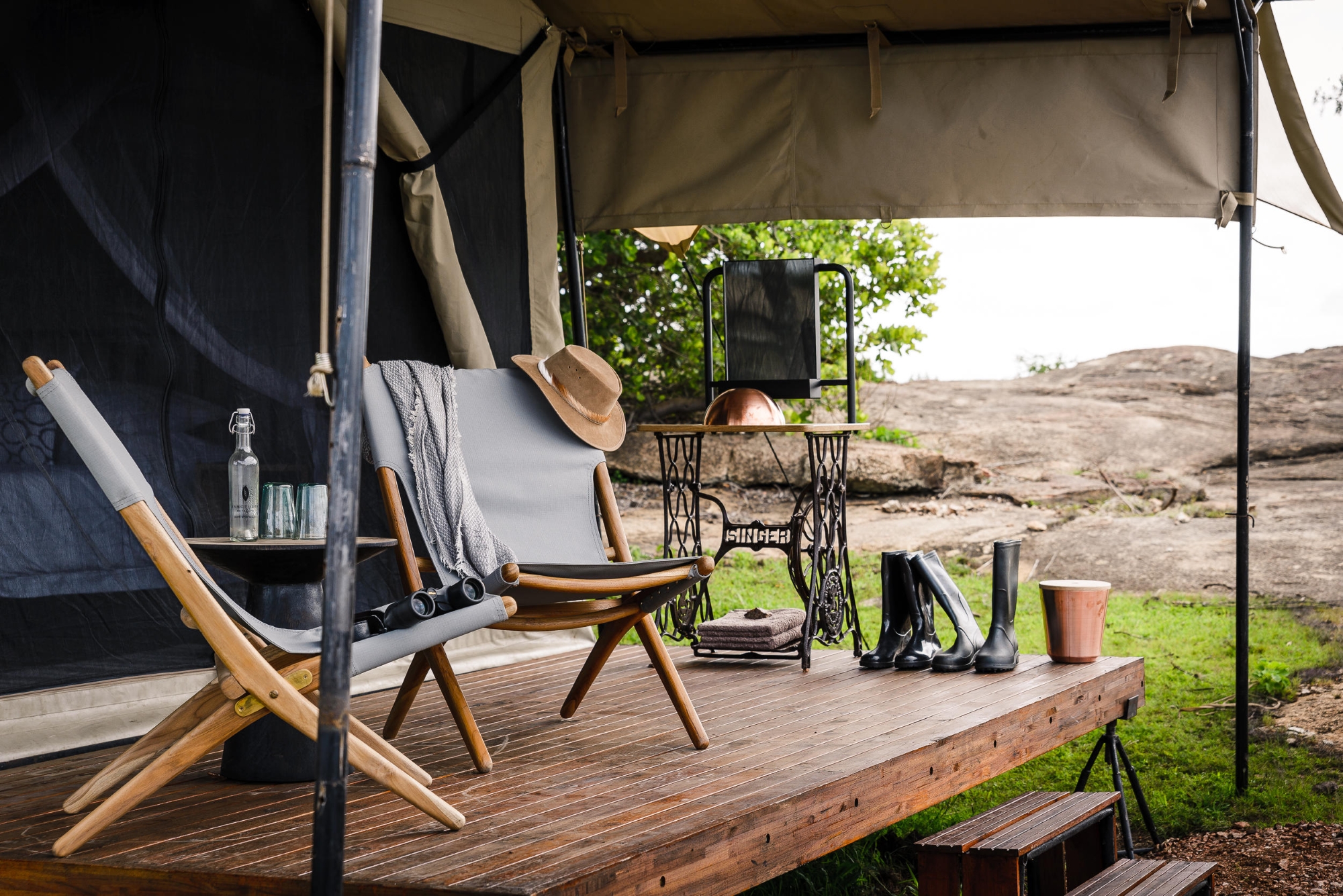 A&K-Sanctuary-Kichakani-Serengeti-Camp-decking A private deck at one of Tanzania’s mobile tented camps is styled with canvas chairs, leather boots, a vintage sewing table, and safari essentials.