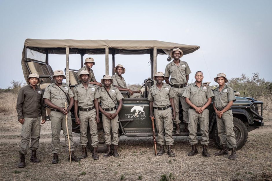 Rhino Guardians - Tracker Academy A group of Rhino Guardians from Tracker Academy stand in front of a safari vehicle in uniform.