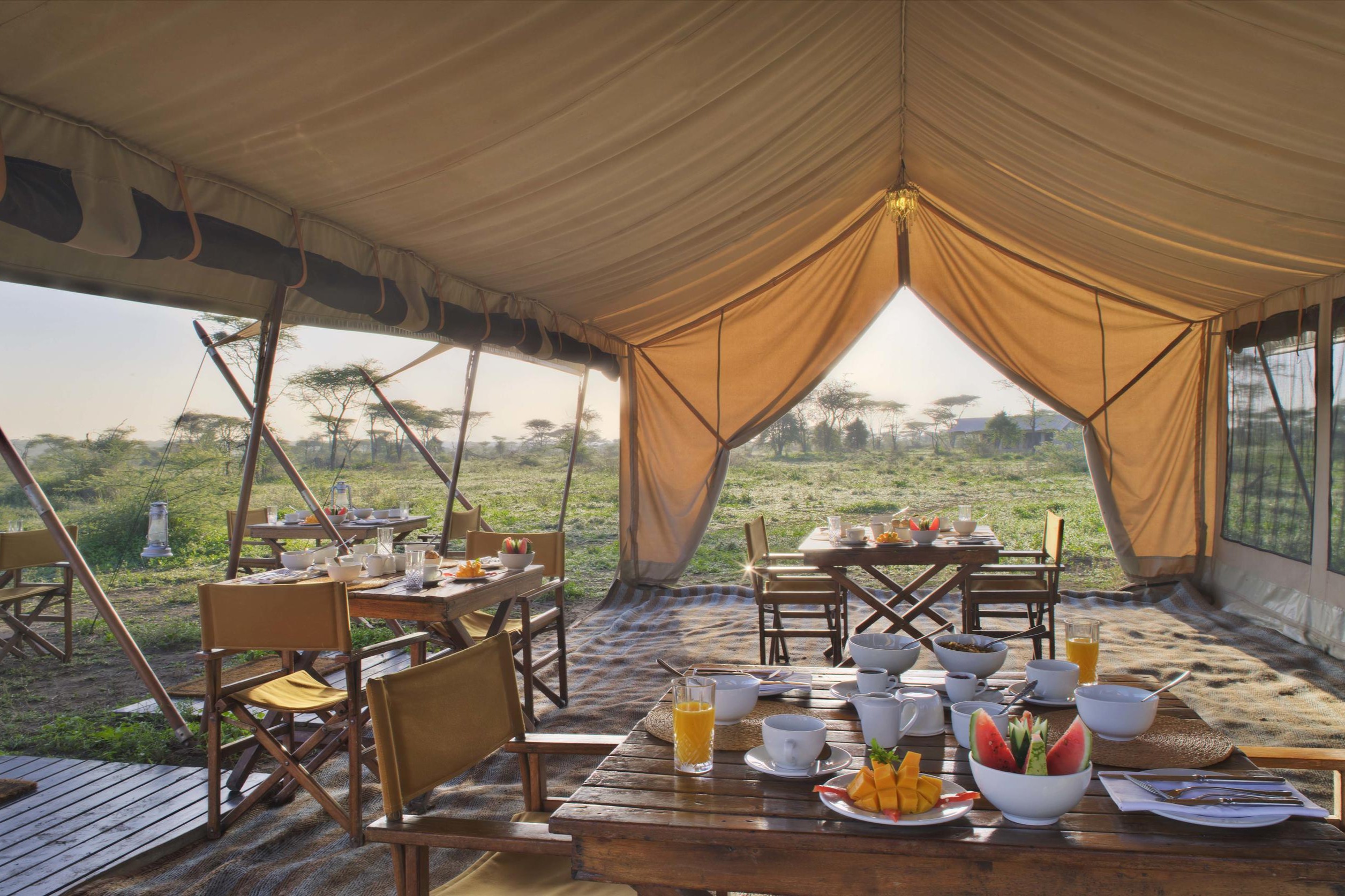 andBeyond-Serengeti-Under-Canvas Breakfast is served inside one of Tanzania’s mobile tented camps, where canvas walls open to the plains and sunlight streams across fruit-laden tables.