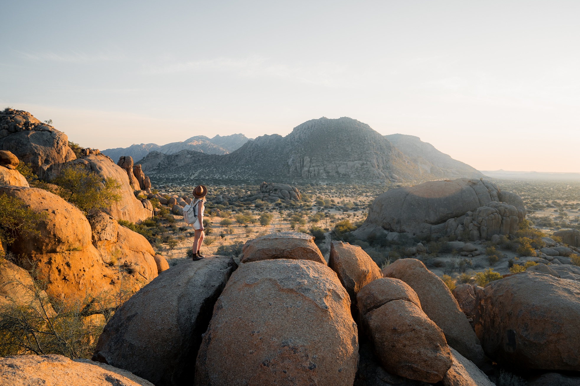 Woman standing on boulder looking out at view in Namibia at Ai Aiba Lodge