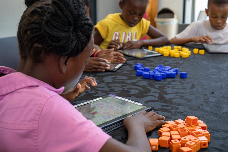 Children at the Good Work Foundation’s Hazyview campus using tablets and colorful learning blocks for an educational activity.