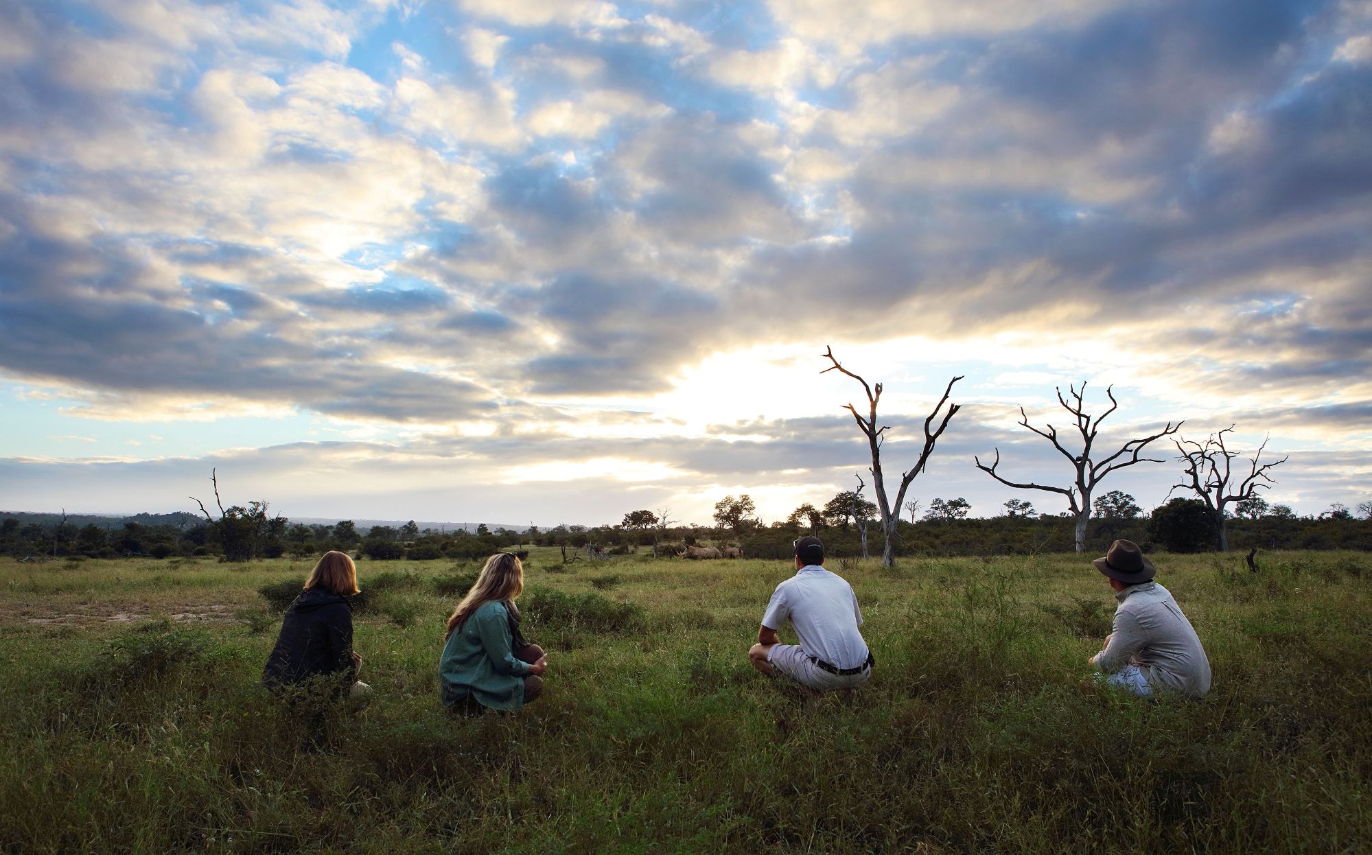 Four individuals crouching among the savannah grasslands