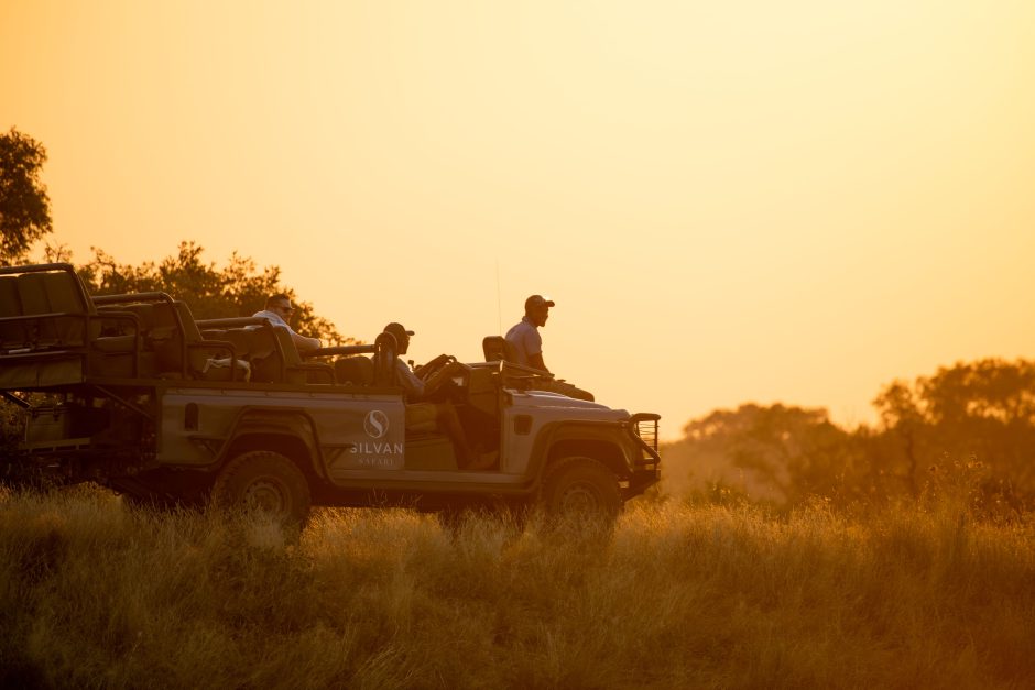 A Silvan Safari vehicle in the bush against an orange sky