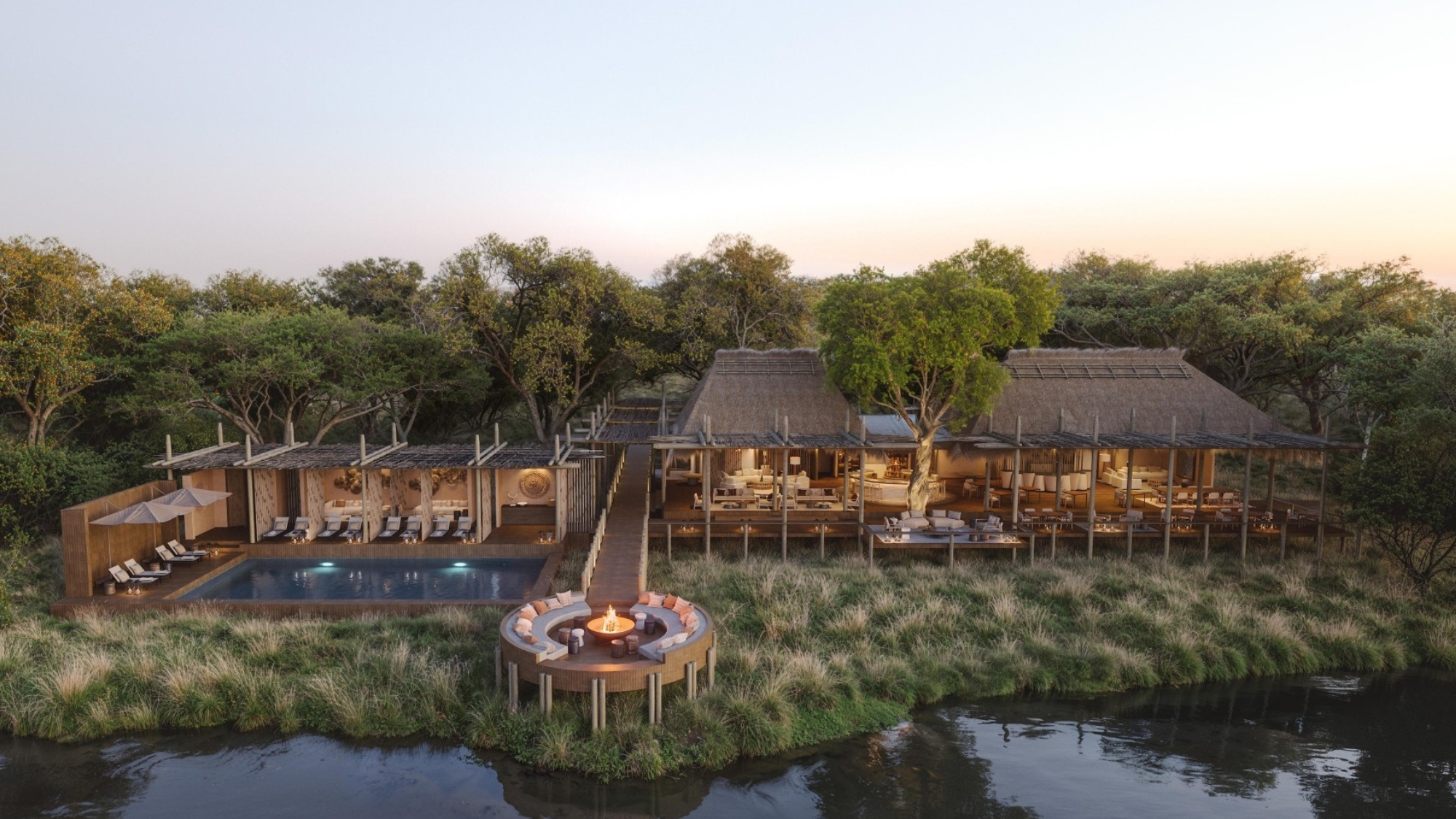 Sediba-Sa-Rona-luxury-lodges-2026-main-area An elevated riverside lodge with open-sided decks, a pool, and a circular fire pit sits nestled among trees overlooking the Khwai River.