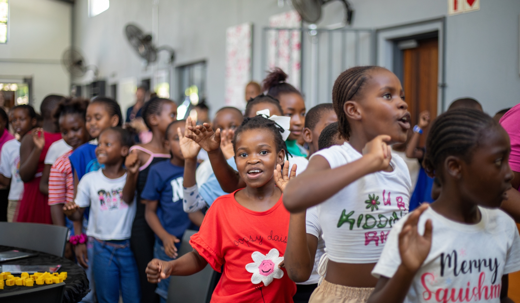 Children at a Good Work Foundation campus sing and move together in a bright, joyful room, capturing a manifesto moment rooted in possibility.