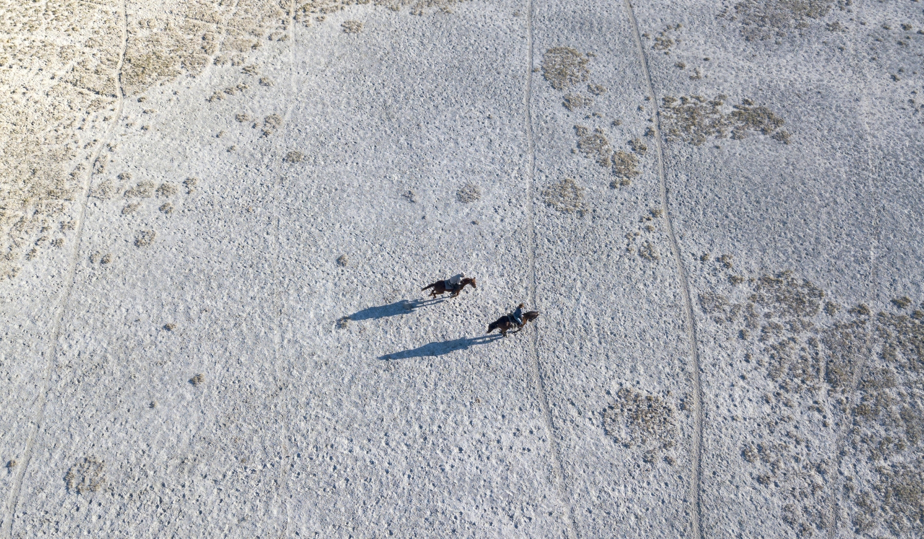 Two riders cross the vast, pale surface of the Makgadikgadi Pans, a stark reminder of where to go in 2026.