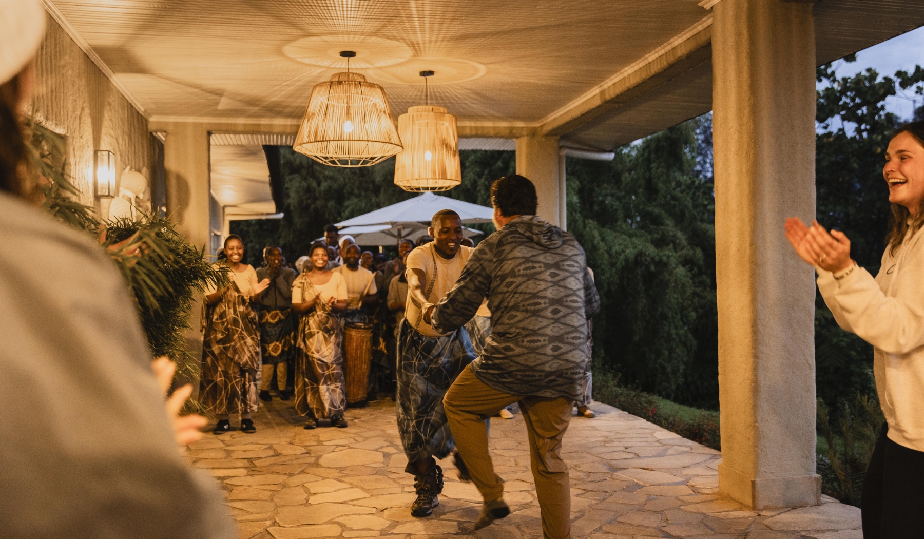 A guest joins local dancers in an animated, laughter-filled welcome, capturing a manifesto experience shaped by shared joy and movement.