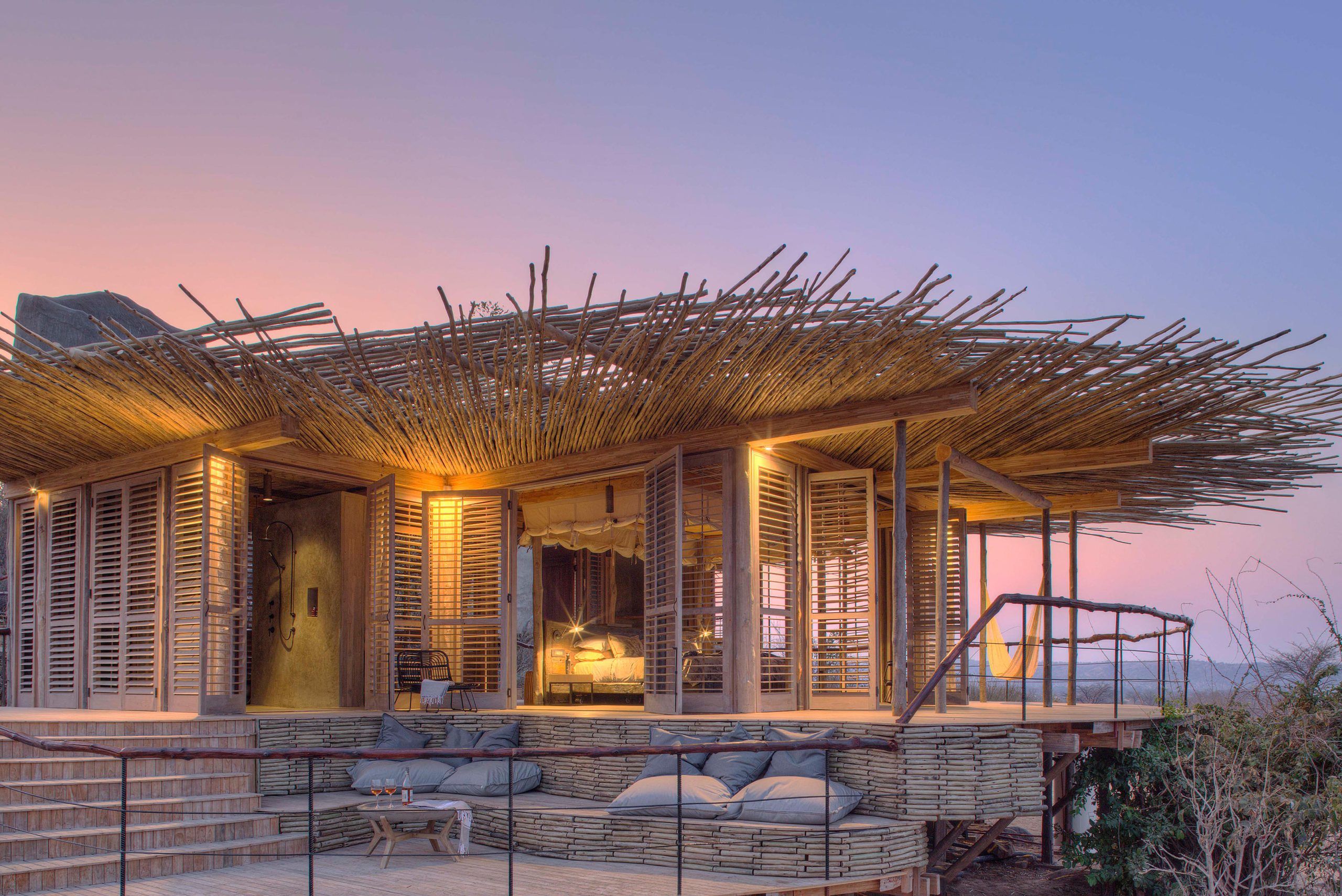 A lantern-lit suite at Jabali Ridge opens onto a wide wooden deck beneath a woven canopy, embodying the refined seclusion found at Luxury safari lodges in Tanzania.