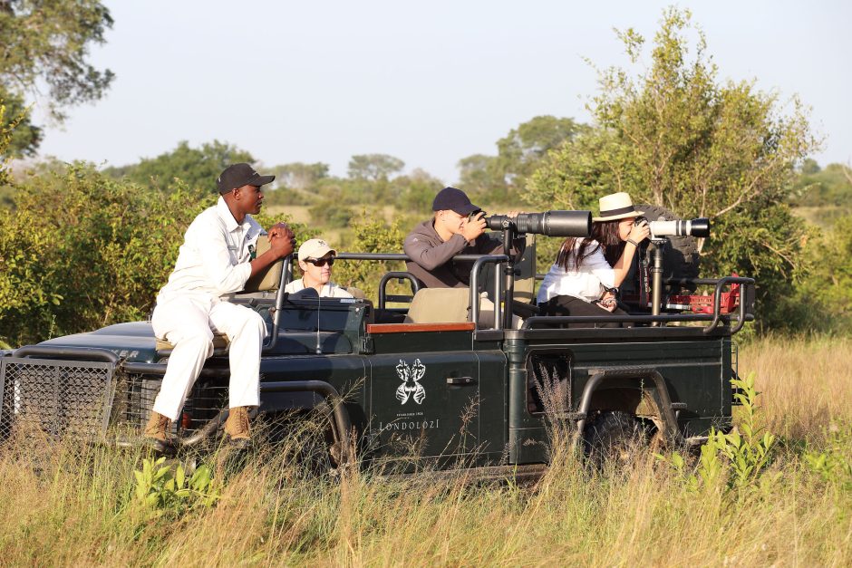 Guests on a Londolozi photographic safari vehicle use long lenses to capture wildlife in the South African bush.